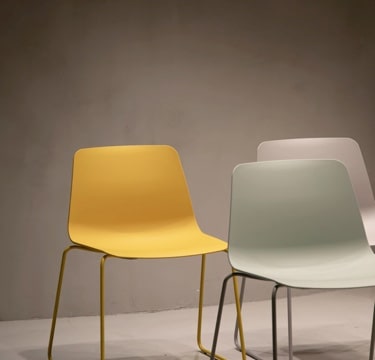 Image of three chairs, orange, silver and grey in a sepia room