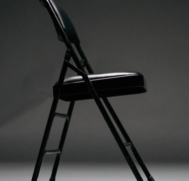 Image of a simple black chair in a darkder room